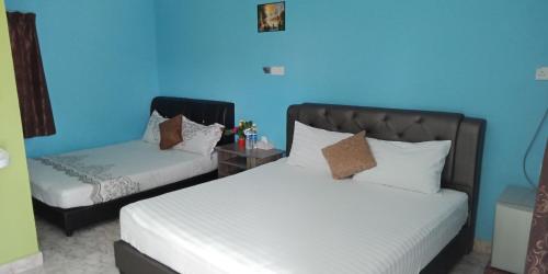 a bedroom with two beds and a blue wall at Mazza Nur Motel in Pantai Cenang