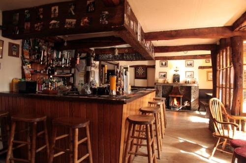 a bar with wooden stools in a room with a fireplace at The Sun Inn in Dent