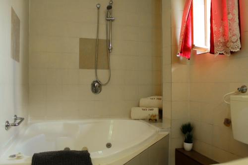 baño con bañera blanca y ventana en Neve Hagar, en Belén de Galilea