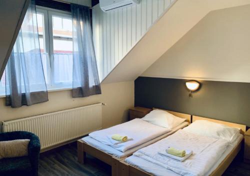 a bedroom with two beds and a large window at R&eacute;v&eacute;sz Hotel, Restaurant and Rosa Spa in Győr