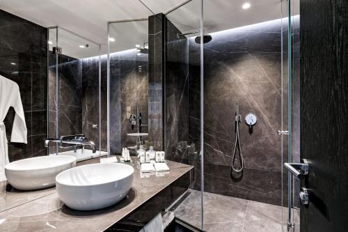 a bathroom with two sinks and a glass shower at Sofitel Athens Airport in Athens