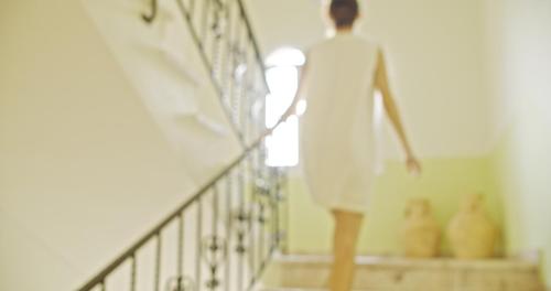 a woman walking down the stairs in a white dress at Waterlily Hotel Apartments in Kalathas