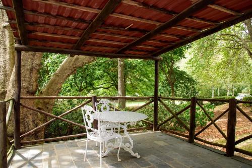 a table and chairs on a porch with a wooden roof at Kings Lodge Hotel in Hogsback