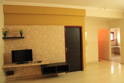 a living room with a flat screen tv on a wall at Temple Stays - Friendliness & Cleanliness Room in Kumbakonam