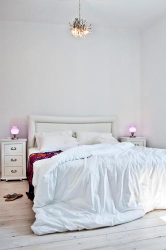 a white bedroom with a white bed and two night stands at Thermes Luxury Villas And Spa in Megalokhori