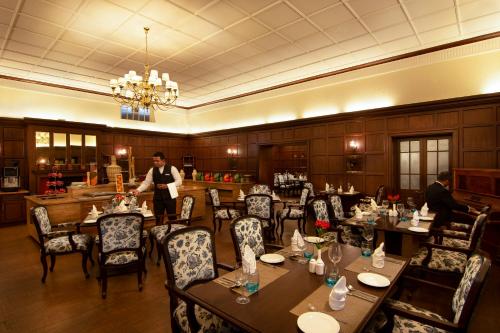 a man standing in a restaurant with tables and chairs at Savoy - IHCL SeleQtions in Ooty