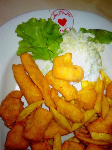 a plate of food with fries and rice and lettuce at Hotel Dewanekhas Skardu in Skardu