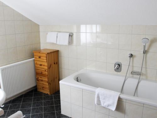 a bathroom with a bath tub and a wooden cabinet at Chalet Rotenstein in Berwang