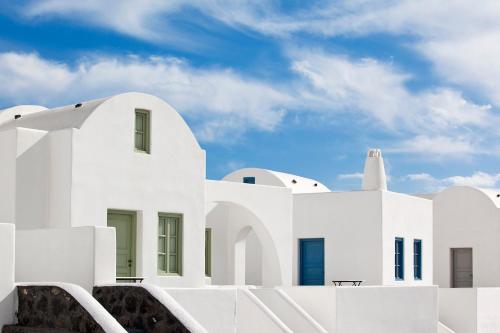 a white building with a lighthouse in the background at Thermes Luxury Villas And Spa in Megalokhori