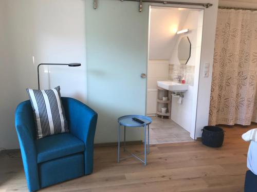 a blue chair and stool in a room with a sink at Posthof Apart . Zimmer in Zirl