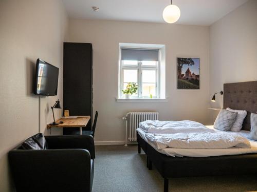 um quarto com uma cama, uma cadeira e uma televisão em Hotel Residens Møen em Stege