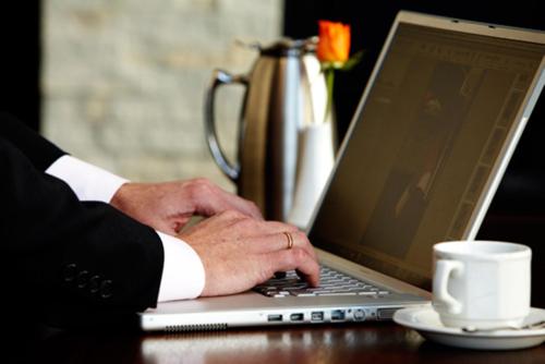 a man in a suit typing on a laptop computer at Premier Hotel Midrand in Midrand