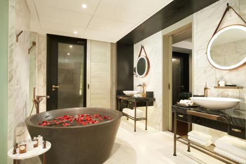 a bathroom with a large tub with red flowers in it at The Barracks Hotel Sentosa by Far East Hospitality in Singapore