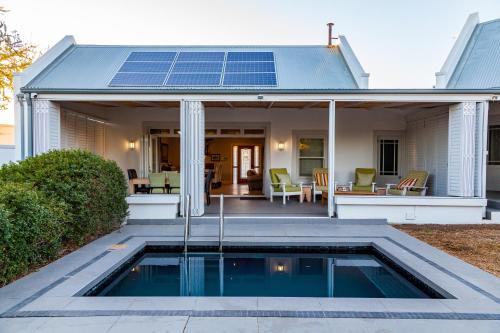 a house with a swimming pool with solar panels on the roof at Karoo Masterclass House and Karoo Masterclass Cottage - Accommodation Prince Albert in Prince Albert