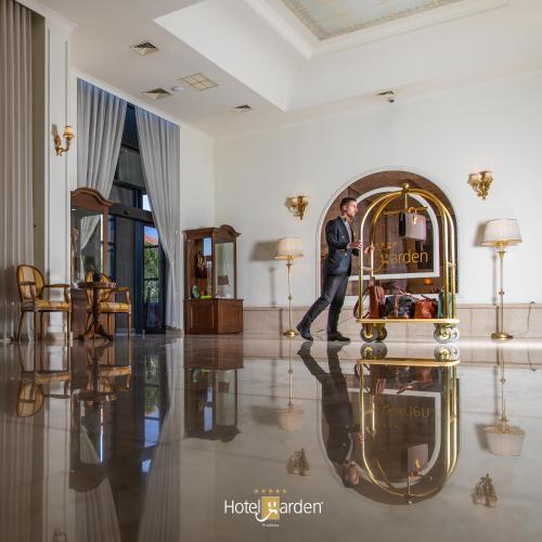 a man walking in a room with a clock on the floor at Hotel Garden in Pristina