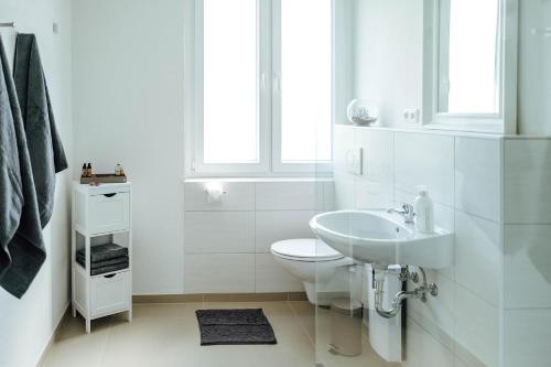 Baño blanco con lavabo y aseo en Kleines Zimmer an der TA mit Balkon (Nr.3), en Hameln