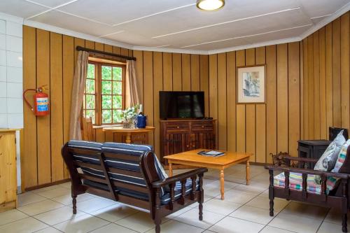 a living room with wooden paneling and a table and a television at Kings Lodge Hotel in Hogsback