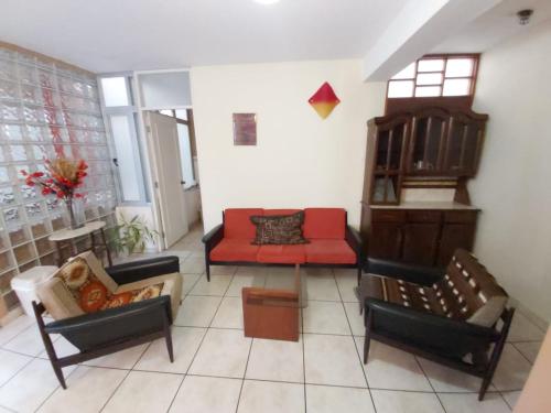 a living room with chairs and a red couch at Taytaypa Rooms & Apartments Lima Airport in Lima