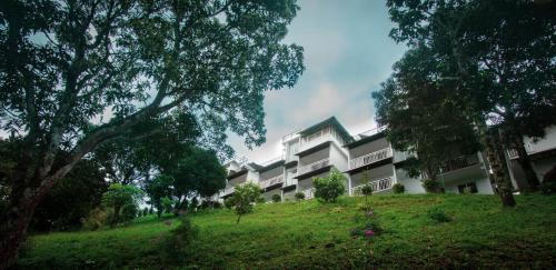 a building on top of a grassy hill with trees at The Lake View Munnar in Munnar