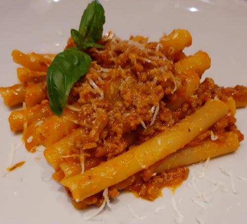 a plate of pasta with meat and a green garnishment at locanda della pacchiana in San Salvatore Telesino