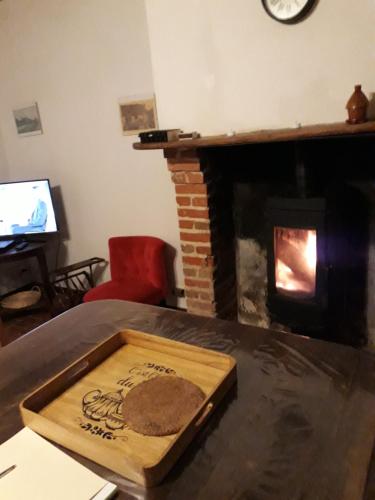 a living room with a fireplace with a wooden tray on a table at La maison de Xenos in Nohant-en-Graçay