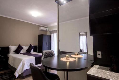 um quarto de hotel com uma cama, uma mesa e cadeiras em Scenery Maqalika Guesthouse em Maseru