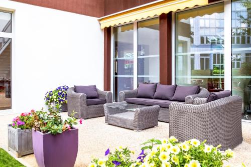 a patio with wicker furniture and some flowers and plants at ibis Paris Meudon Velizy in Meudon