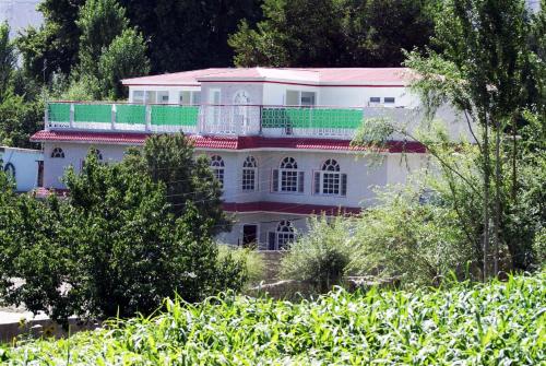 a large white house with a pink roof at Hotel Dewanekhas Skardu in Skardu