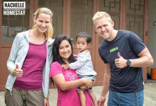 a family posing for a picture in front of a house at Nachelle Homestay in Berastagi