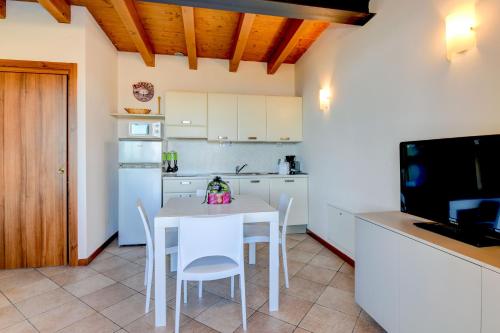 a kitchen with a white table and chairs and a television at Relais Rosa Dei Venti -Ciao Vacanze- in Moniga