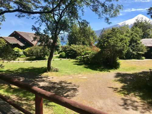 a yard with a fence and a mountain in the background at YAN KEE WAY LODGE BUNGALOW in Puerto Varas