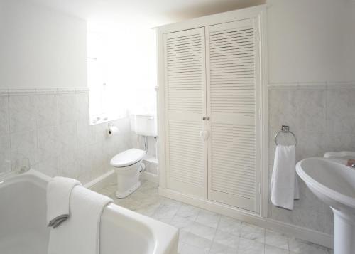a white bathroom with a toilet and a sink at Chapel Cottage Set in a private courtyard in central location with 2 parking spaces in Kirkby Lonsdale