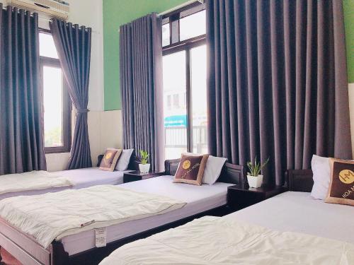 two beds in a room with two windows at Hoa Mai Hotel in Dong Hoi