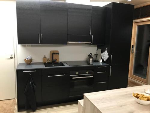 a kitchen with black cabinets and a black stove at Villa Váibmu in Inari
