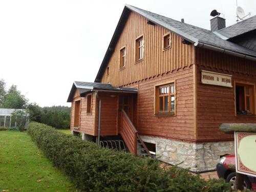 a large wooden house with a car parked next to it at Penzion U mlýna in Rejvíz
