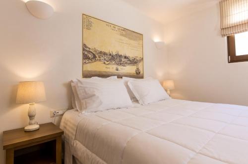 a bedroom with a white bed with a picture on the wall at Anagram Hotel in Mikonos