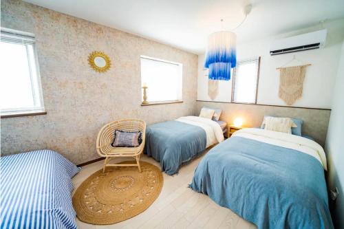 a bedroom with two beds and a chair in it at Shisa Terrace Ginoza in Ginoza