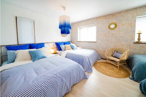 a bedroom with two beds and a chair in it at Shisa Terrace Ginoza in Ginoza