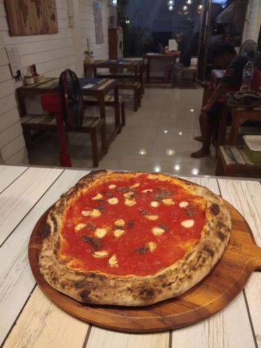 a pizza sitting on a wooden board on a table at La Locanda in Bangkok