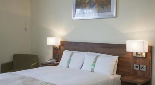 a bedroom with a bed with two lamps on it at Holiday Inn Ashford Central by IHG in Ashford