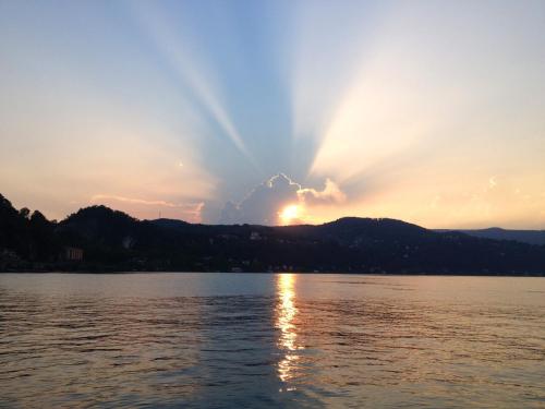 a sunset over a lake with the sun setting at Camping Village Lago Maggiore in Dormelletto