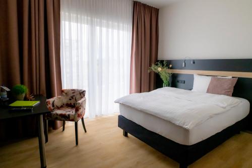 a bedroom with a bed and a desk and a chair at Hotel Campo in Renningen