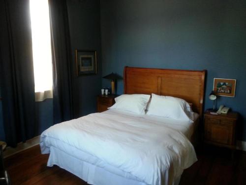 Un dormitorio con una gran cama blanca y una ventana en Hotel Manoir Atkinson, en Valparaíso