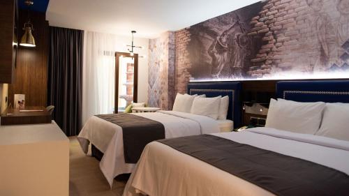 a hotel room with two beds and a stone wall at Hotel Indigo Guanajuato, an IHG Hotel in Guanajuato