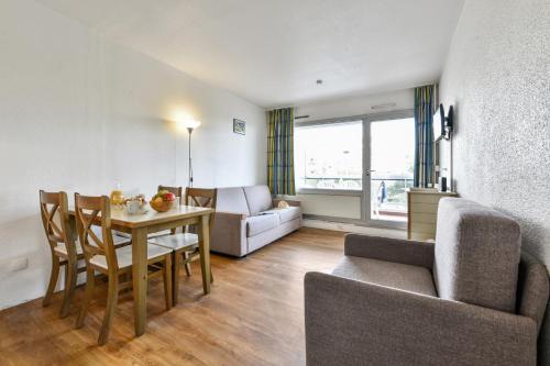 un salon avec une table, des chaises et un canapé dans l'établissement Résidence partenaire Le Tanit, à Juan-les-Pins