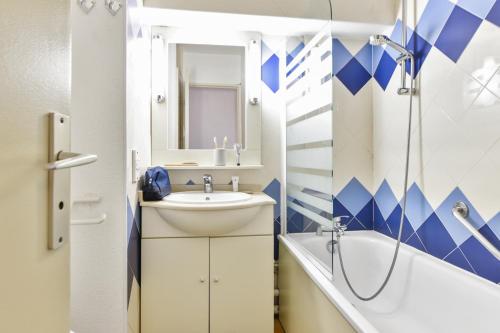ein Badezimmer mit einem Waschbecken, einer Badewanne und einem Spiegel in der Unterkunft Maeva Selection Résidence Le Tanit in Juan-les-Pins