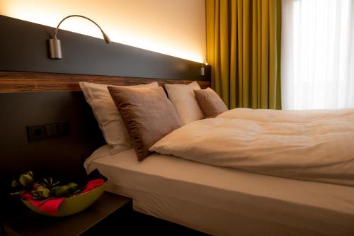 a bed in a hotel room with a bowl of fruit at Hotel Campo in Renningen