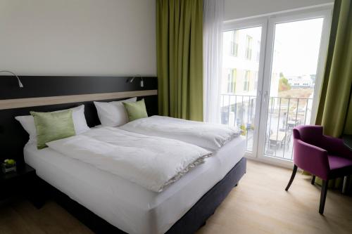 a bedroom with a large bed and a large window at Hotel Campo in Renningen