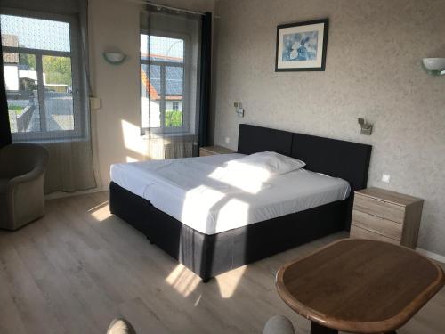 a bedroom with a large bed and a wooden table at Hotel Zum Weinberg in Cremlingen
