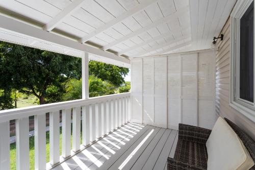 a white porch with a bench and a window at South Coast Horizon in Curtain Bluff